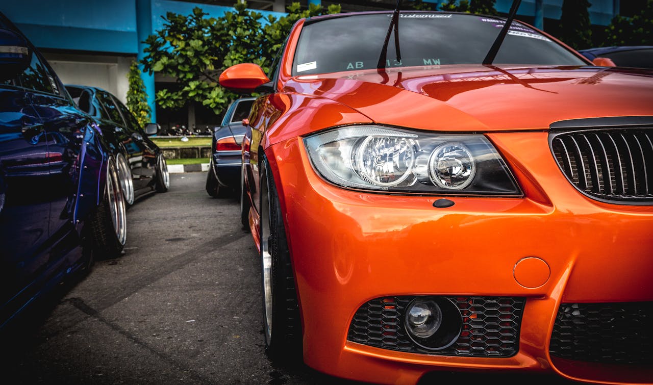 Close-up of a vibrant orange sports car showcased at an outdoor auto event, highlighting its sleek design.